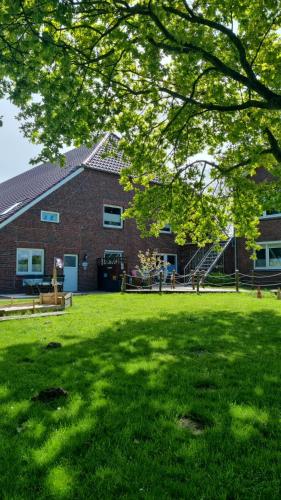 a brick house with a green lawn in front of it at Ferienhof Harlenest in Wittmund