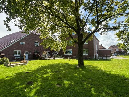 a tree in a yard in front of a house at Ferienhof Harlenest in Wittmund