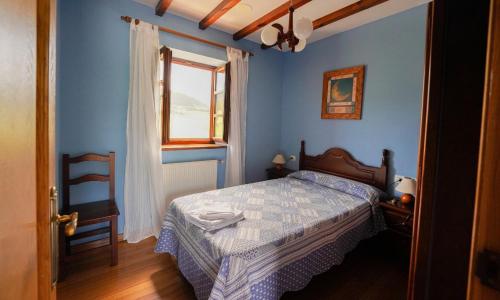 a blue bedroom with a bed and a window at El Cuelebre in Arancedo