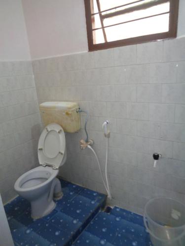 a bathroom with a toilet with a hose at Urban Hostels in Tiruvannāmalai