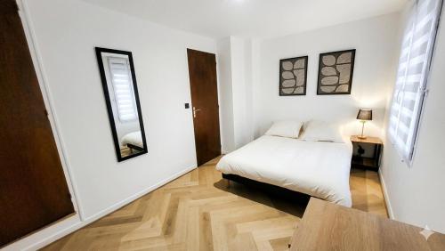a white bedroom with a bed and a table at Ô Cœur d'Objat - Baby-foot - Clim in Objat