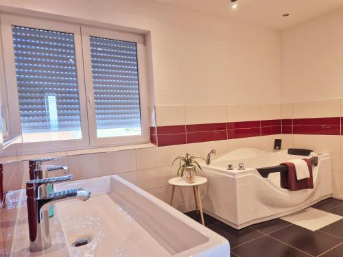 a bathroom with a tub and a sink and two windows at JM Swiss Space Hostel in Langrickenbach