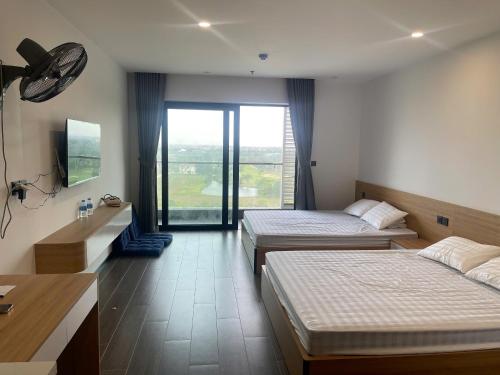 a hotel room with two beds and a window at L'Azur Cửa Lò in Cửa Lô