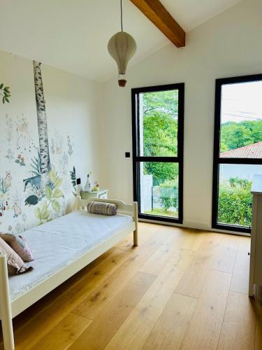 a bedroom with a bed and two large windows at Villa premium avec extérieur ensoleillé in Urrugne