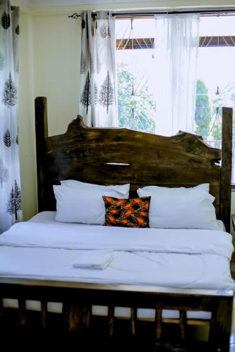 a bed with a wooden headboard in a bedroom at Ziwani House in Mwanza