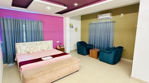 a bedroom with a bed and two blue chairs at Palmyra Hotel and Suites in Kollam