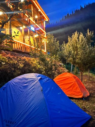a blue and orange tent in front of a cabin at The WILD Canopy in Kulu