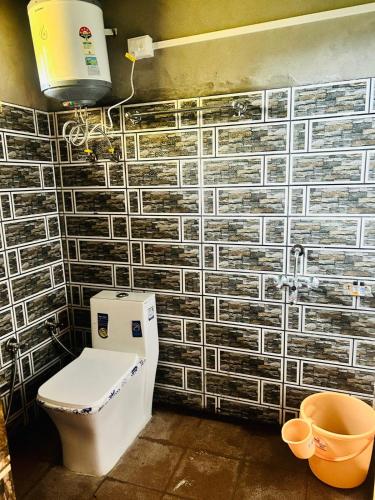 a bathroom with a toilet and a wall with tiles at The WILD Canopy in Kulu