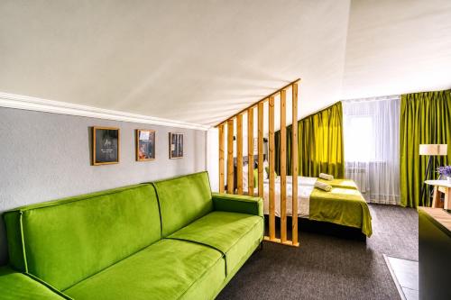 a living room with a green couch and a bed at APART-HOTEl 95 in Almaty