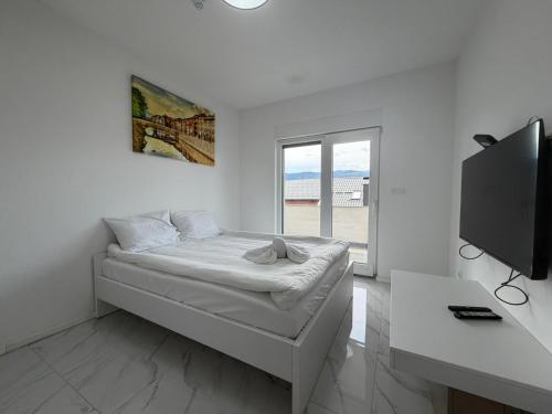 a white room with a bed and a flat screen tv at Vila Gaia in Sarajevo