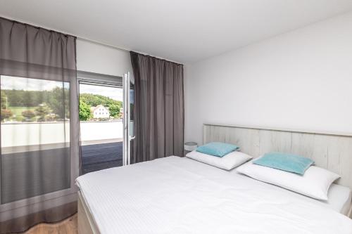 a bedroom with a white bed and a large window at CalmApart Firmenrechnung mit MwSt in Kleinkötz