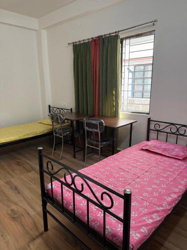 a bedroom with a bed and a table and a window at Nasa in Panchanai