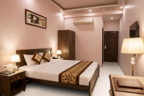 a hotel room with a bed and a table and lamps at Platinum Royal Excellency in Udaipur