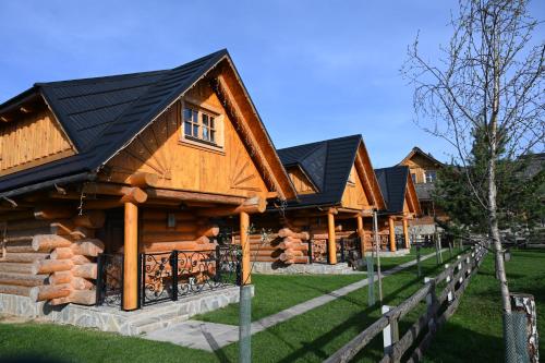 a row of log homes with black roof at Zbojnicky penzion in Jasenica
