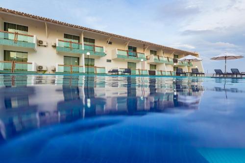 a hotel swimming pool with chairs and umbrellas at Arrey Hotel Beach in Parnaíba