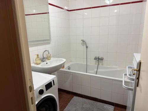 a bathroom with a tub and a sink and a washing machine at Le Magnifique 3 personnes Drancy in Drancy