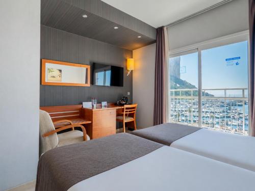 a hotel room with a bed and a desk and a window at Hotel Porto Calpe in Calpe