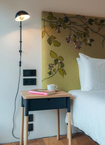a table with a cup on it next to a bed at The Grand Indradhar Resort Dharamshala in Dharamshala