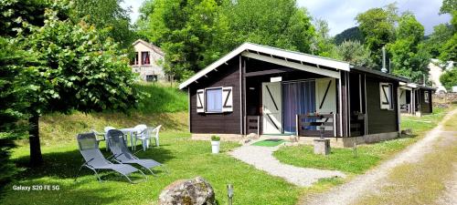 a small cabin with a table and chairs in the grass at LES CHALETS de MONTORGUEIL in Saurat