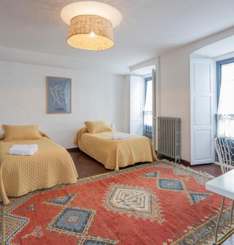 a bedroom with two beds and a rug at PISO CON TERRAZA in Ribadeo