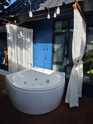 a bath tub sitting in a bathroom with curtains at Baannaisuk Pool Villa in Ban Mae Pu Kha