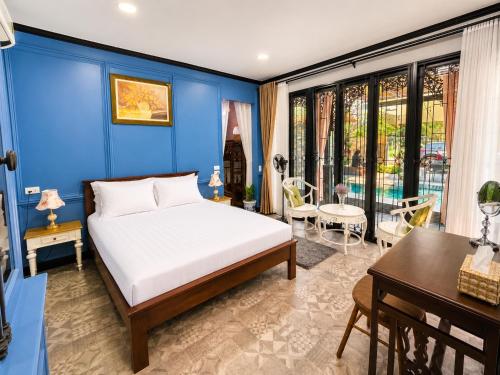 a bedroom with a blue wall with a bed and a table at Baannaisuk Pool Villa in Ban Mae Pu Kha