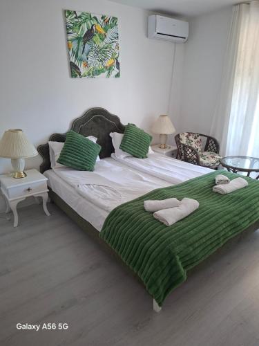 a bedroom with a large bed with green sheets and pillows at хотел Кристиан in Sozopol