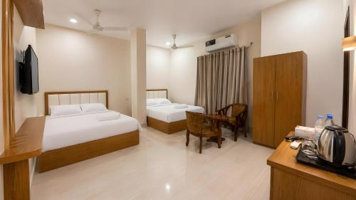 a bedroom with two beds and a desk with a television at Hotel Grand Darbar in Barisāl