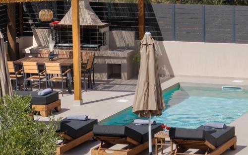 a pool with an umbrella and chairs and a table at Villa Dreamscape - Elegant Stay with Private Pool by Villa Mana Gers in Planos