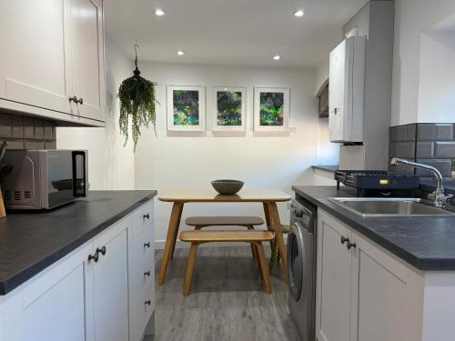 a kitchen with white cabinets and a wooden table at 10 Crickhowell Cottages, Standard Street, Central Crickhowell in Crickhowell