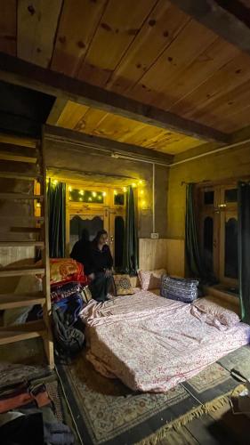 a man sitting in a bedroom with two beds at Mansa Homestay in Kalgha