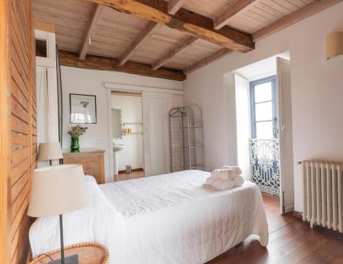 a bedroom with a large white bed and wooden ceilings at NAMOR-Estudio Galeria in Ribadeo