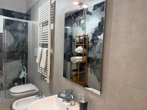 a bathroom with a sink and a toilet and a mirror at Terrazza Vanvitelli in Caserta
