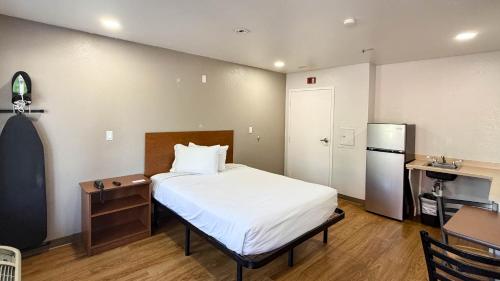 a bedroom with a bed and a kitchen with a refrigerator at Studio 6 Rancho Cordova, CA in Rancho Cordova
