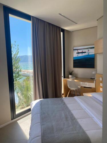 a hotel room with a bed and a desk and a large window at Hotel Bologna in Vlorë