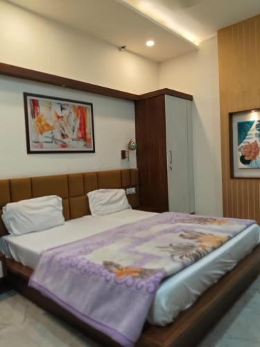 a bedroom with a large bed with a purple blanket at Crown Palace Hotel & Restaurant in Hāpur