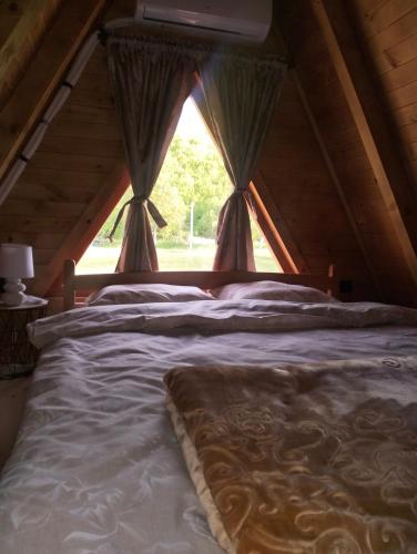 a large bed in a room with a window at RIVERSTONE Drašković camp and bungalows in Nikšić