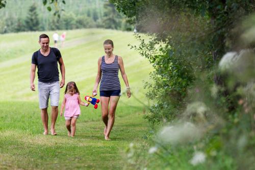 a woman and a man walking with a little girl at AIGO Welcome Family Resort in Aigen im Mühlkreis