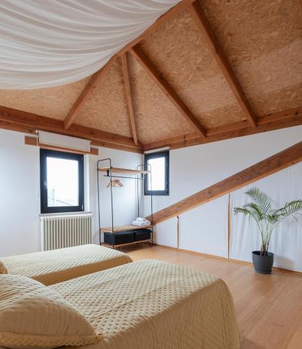 two beds in a room with wooden ceilings at NAMOR - Buhardilla Zen in Ribadeo