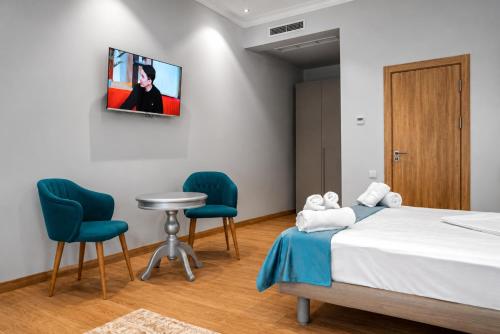 a room with a bed and two chairs and a tv at The Wood Hotel & Spa near Magic City in Tashkent