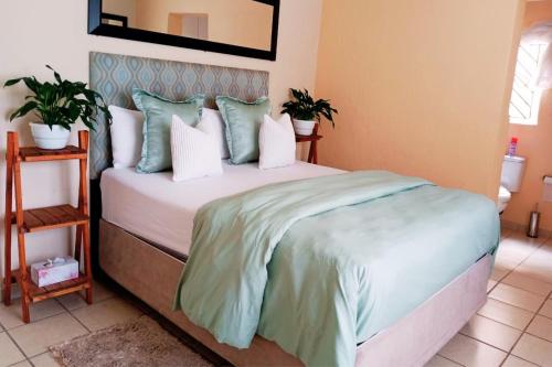 a bedroom with a bed with green and white pillows at Budget Stays at Olivia Pines Guesthouse in Krugersdorp