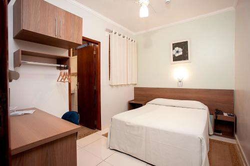 Alves Hotel في ماريليا: غرفة نوم فيها سرير ومكتب