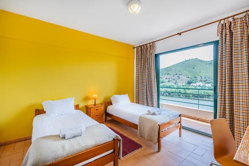 a bedroom with two beds and a large window at HI Alcoutim – Pousada de Juventude in Alcoutim