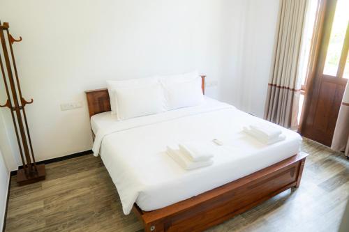 a bedroom with a white bed with two books on it at Diana Residence in Matara