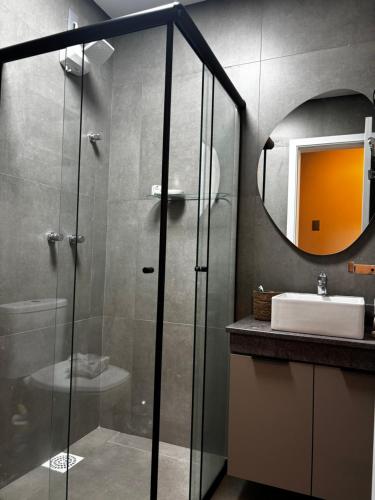 a bathroom with a glass shower and a sink at Loft Livin em Atlântida ao lado do Ramblas in Xangri-lá