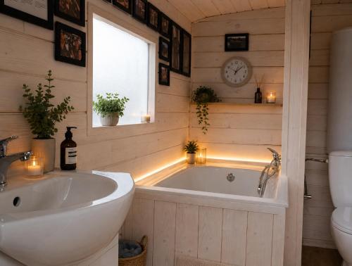 a bathroom with a tub and a sink and a clock at Andělka maringotka in Humpolec