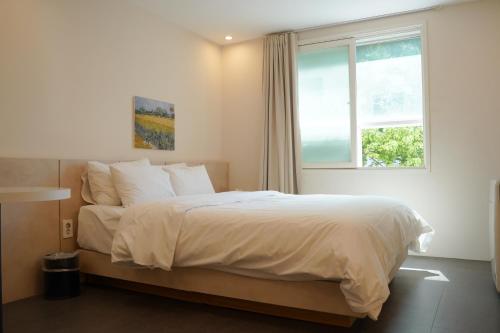a bedroom with a large bed with a window at Hotel Azure Incheon in Incheon