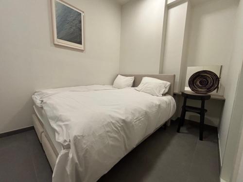 a white bedroom with a bed and a table at Villa Mer, Bardot - Luxury apartment in Badhuis with swimming pool and sauna near the beach in Cadzand