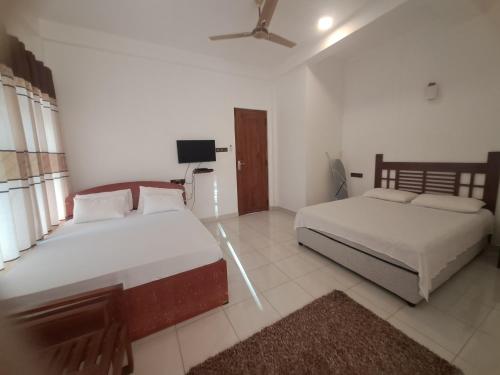 a bedroom with two beds and a ceiling fan at Risenlak Holiday Resort in Polonnaruwa