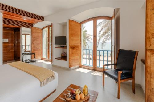 a bedroom with a bed and a chair and a balcony at The Promenade in Pondicherry